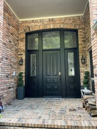 Black-painted double front door in a brick entry
