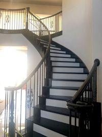 Sweeping curved staircase with black railings and white risers