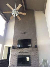 Two-story living room with a painted brick fireplace and high walls