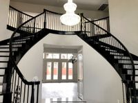 Grand foyer with twin curved staircases and freshly painted black railings