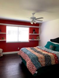 Bedroom with a bold red accent wall and white floating shelves