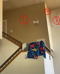 Tall stairwell wall with patched spots marked in red before painting