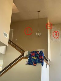 Tall stairwell wall with patched spots marked in red before painting