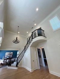 Two-story foyer with a curved balcony staircase and freshly painted walls