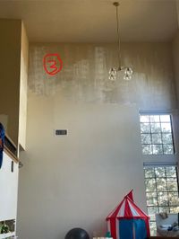 Two-story wall left half-painted with patchy primer before the crew started