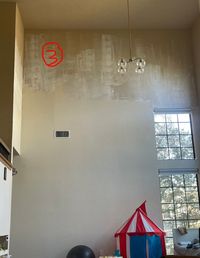 Two-story wall left half-painted with patchy primer before the crew started